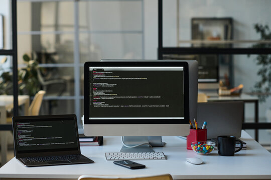 Workplace of developer with computers with programming codes on the screens on table