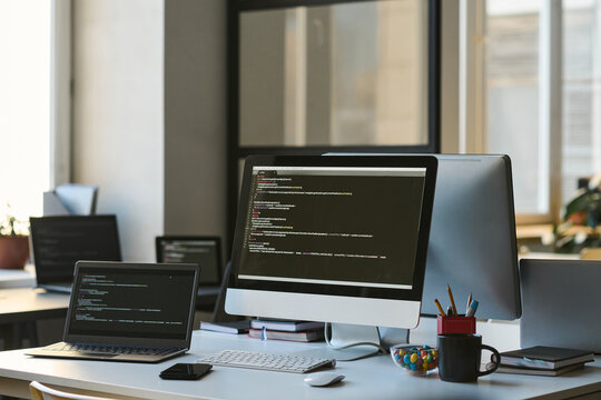 Modern workplace of developer with computers with programming codes on screens in IT office