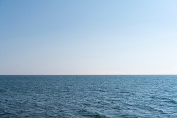Obraz premium Aerial view of a blue sea water background and sun reflections. Aerial flying drone view. Waves water surface texture on sunny tropical ocean. Aerial photography.