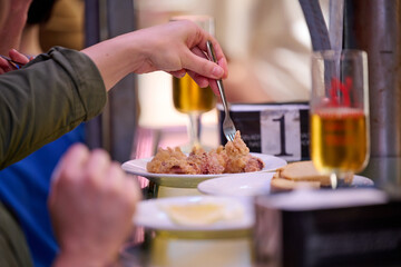 two persons eating tapas with glasses of beer