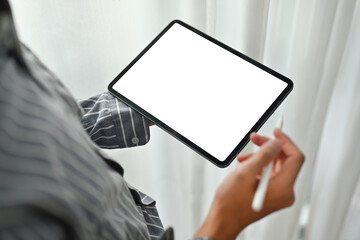Close up view of creative man in shirt standing near curtain at home office and using digital tablet