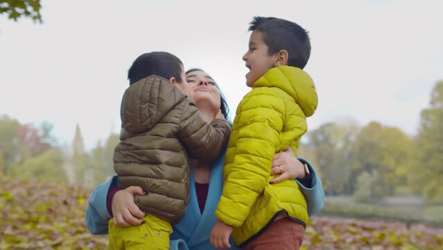 Cute little boys kiss mother outdoors. Realtime