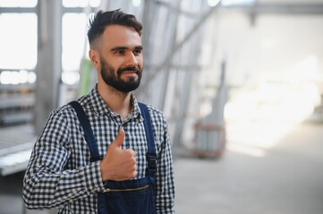 Portrait of industrial engineer. Factory worker with hard hat standing in factory.