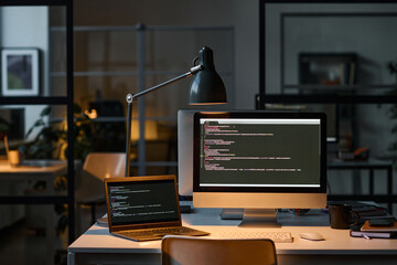 Modern workplace with computers with security codes on the screen in dark IT office
