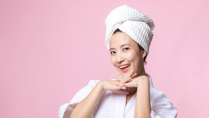 Beautiful young asian woman happy with clean face skin in towel and bathrobe, spa suit on pink background. Skincare, treatment, wellness therapy, facial care, beauty female health, cosmetology concept