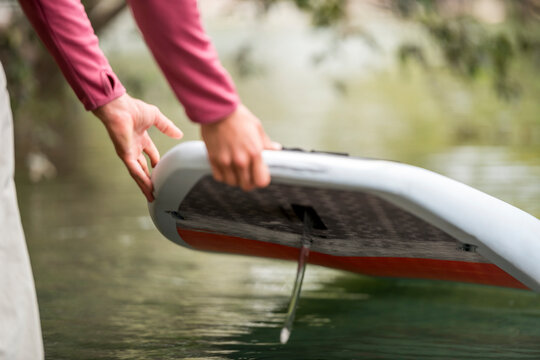 A Fisherman Launches His Stand-up Paddleboard Into The Water In Preparation For Fly Fishing