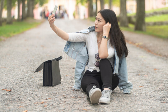 Chinese stylish female using her mobile and taking images