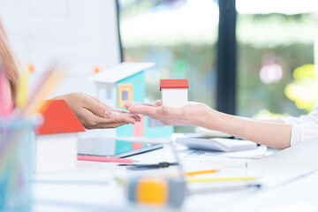 oncept of engineering consulting, Two female engineers discussing about model of building together; Two female architects are studying blueprint of building house.