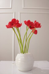 Red flowers with beautiful green stalks in a vase on the table