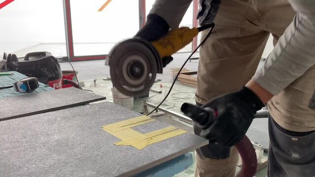 Builder tiler measures the tiles and cuts them with a diamond cutter