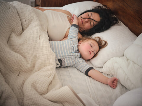 Mother and daughter co sleeping in bed early in morning