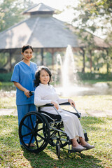 Elderly asian senior woman on wheelchair with Asian careful caregiver. Nursing home hospital garden concept. in sunlight.
