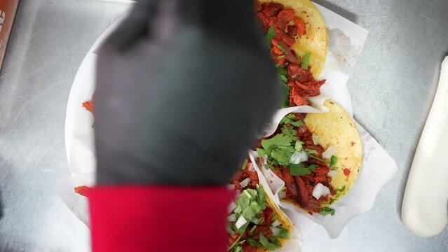 Sprinkling chopped onions on a plate of street tacos - food truck series