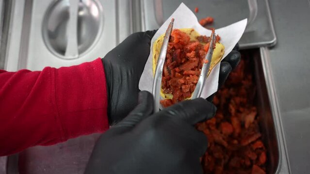 Putting marinated, pulled pork on a soft taco shell - food truck series 