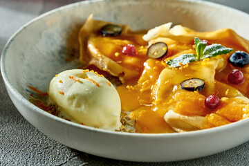 Classic crepe suzette with orange jam, ice cream and berries in a plate. A delicious dessert