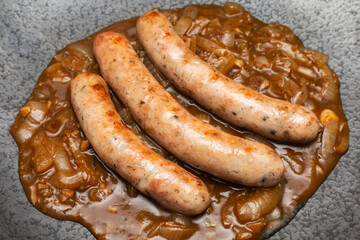Wurst sausage in onion sauces serving on stone pan. Traditional German food.