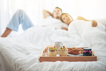 Fototapeta na wymiar Nothing better than breakfast in bed. Shot of a loving young couple enjoying breakfast in bed.