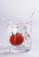 Tomate fällt in Wasserglas