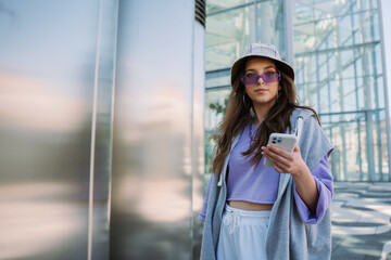 Cool young girl looking to camera and holding mobile phone. 