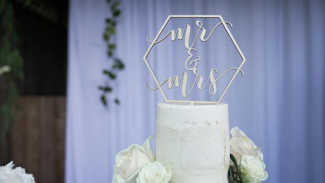 Beautiful wedding cake decorated with natural flowers and a cake topper on the tip.