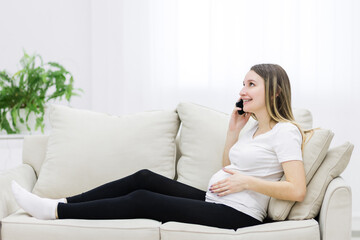 Obraz premium Side view of pregnant woman talking over the phone.