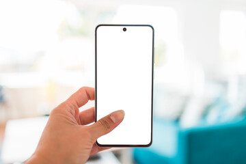 hand holding smartphone with copy space in front of stylish living room home interior background, shot at shallow depth of field