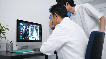 パソコンを見て会議する医療従事者のグループ