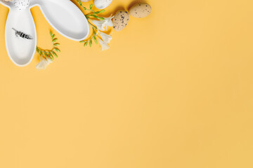 creative easter layout with white plate bunny and easter eggs on yellow background. copy space. top view. flat lay
