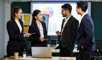 Millennial Asian Indian professional male businessmen female businesswomen employee staff colleagues in formal business suit standing discussing brainstorming working together with laptop computer