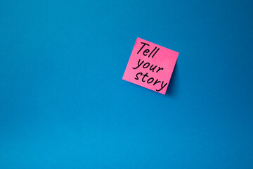Tell your story symbol. Concept words Tell your story on pink steaky note. Beautiful blue...