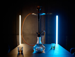 Hookah on table with glasses filled brandy in neon light