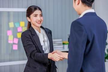Millennial professional successful male businessman and female businesswoman in formal business suit shaking hands greeting deal done job agreement achievement