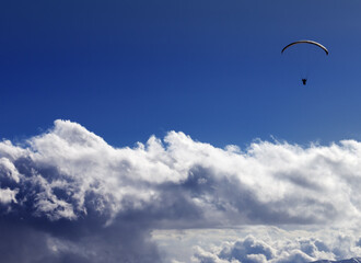Silhouette of paraglider and blue sunny sky. Caucasus Mountains. Georgia, view from ski resort Gudauri.
