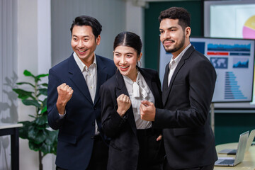 Millennial Asian  professional male businessmen female businesswomen employee staff colleagues in formal business suit sitting holding fists up celebrating job deal achievement