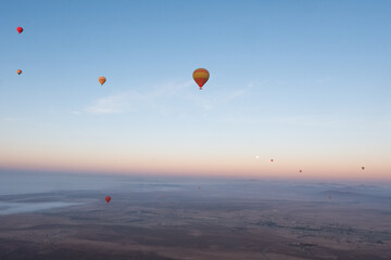 Many hot air balloons fly over the desert in Morocco