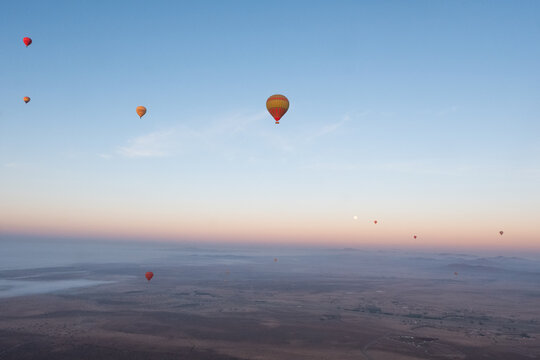 Many hot air balloons fly over the desert in Morocco