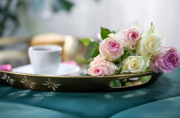 Bouquet of roses and a cup of coffee on a gold tray