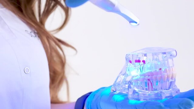Photopolymer lamp Doctor Fairy with a glowing blue lamp in a white medical suit Dentist treatment of teeth prosthetics put fillings treat gums caries beautiful woman on white background studio ad
