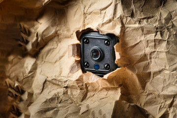 A spy camera hide in torn paper hole . Hidden camera or detective or scandal concept.