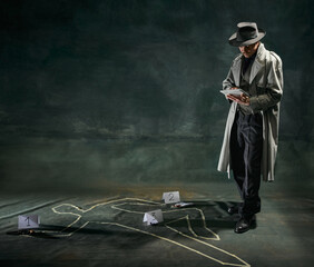 Portrait of man, detective in trench coat standing near human drawn silhouette on floor and making...