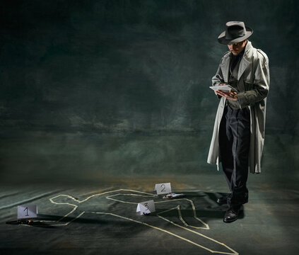 Portrait of man, detective in trench coat standing near human drawn silhouette on floor and making case notes over vintage dark green background. Concept of occupation, character, history. Retro style