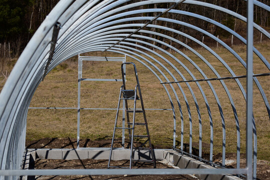 Fertiges Gerüst eines Folientunnels mit Leiter zum Aufbauen, Montage eines Glashauses
