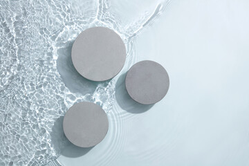 Three circle podiums in gray color decorated on water background. Empty area for cosmetic product...
