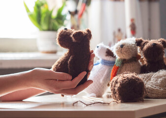 A knitted toy in the hands of a young woman. Knitting concept , handmade, an activity for the soul and mental health.