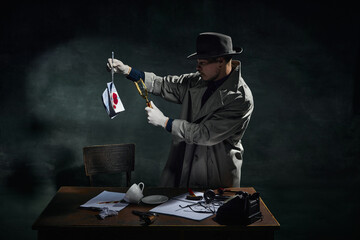 Professional detective in trench coat looking in magnifying glass at handkerchief with blood spots...