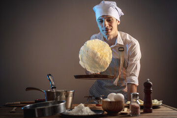 Cook is throwing a pancake into the air to turn it over. The concept of the process of preparing a...