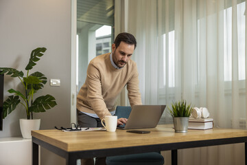 Young man using laptop computer for e-learning or paying bills online