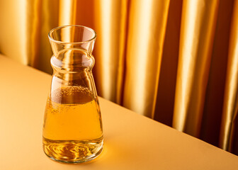 Glass decanter with apple juice on yellow background. Healthy drink concept with copy space