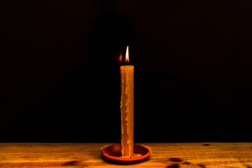 Candle light on the wooden table in the dark night.Single burning candle. Light of flame and...