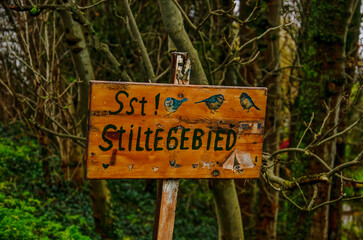 Improvised wooden sign with pictures of birds and the text "Stiltegebied" (Quiet Area in Dutch) in a little forest in the Netherlands